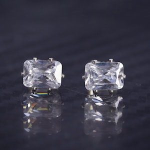 May include: A pair of silver earrings with clear rectangular cubic zirconia stones.