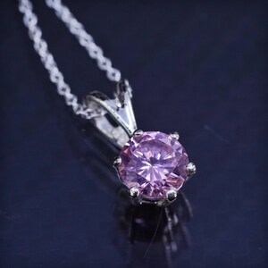 May include: A silver chain necklace with a pink gemstone pendant.