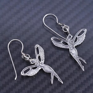 K&ouml;nnte beinhalten: Ein Paar silberne Ohrringe mit einem detaillierten Design einer Fee mit Fl&uuml;geln. Die Ohrringe sind aus Sterlingsilber gefertigt und haben einen zarten, femininen Look.