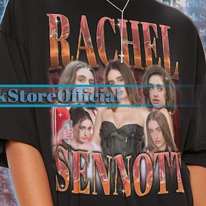May include: Black oversized t-shirt featuring a graphic of Rachel Sennott with text. The shirt has a crew neck and short sleeves. The text "Rachel Sennott" is in orange and the text "SickStoreOfficial" is in blue.