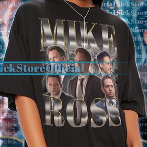 May include: Black unisex t-shirt featuring the text "MIKE ROSS" in a metallic gold font, with images of actors. The shirt has short sleeves and a crew neck. The model is wearing a 2XL shirt.