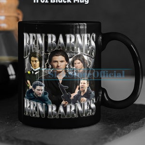 May include: Black ceramic mug with a collage of images of Ben Barnes. The mug has a white handle and the text "Ben Barnes" is printed in silver on the front.