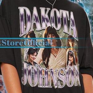May include: Black unisex t-shirt featuring a graphic of Dakota Johnson with the text "DAKOTA JOHNSON" in a vintage style. The shirt is oversized and has short sleeves.