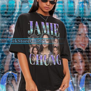 Op de afbeelding: Zwart unisex T-shirt met de naam "JAMIE CHUNG" en afbeeldingen van de actrice. Het shirt heeft korte mouwen en een ronde hals. Het model draagt maat 2XL. Het shirt is ontworpen voor een oversized look.
