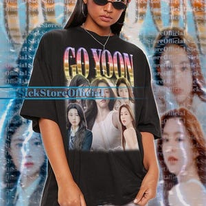 May include: Black unisex t-shirt featuring the text "GO YOON" in a colorful, stylized font. The shirt displays images of several women. The background has a blurred effect with the words "Sick Store Official".