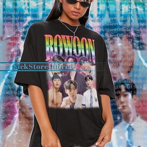 Op de afbeelding: Zwart unisex T-shirt met het woord "ROWOON" in regenboogletters en een afbeelding van verschillende mensen. Het shirt heeft korte mouwen en wordt gedragen door een persoon met een zonnebril.