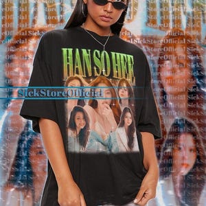 Könnte beinhalten: Schwarzes Unisex-T-Shirt mit dem grünen Schriftzug "HAN SO HER" und einer Grafik von mehreren Frauen. Das Shirt ist übergroß und wird von einer Person mit Sonnenbrille getragen. Der Hintergrund hat ein sich wiederholendes Textmuster.