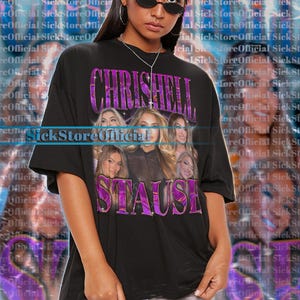 May include: Black unisex t-shirt featuring a graphic of the name "CHRISHELL STAUSE" in purple, with images of women. The shirt is oversized and has short sleeves.
