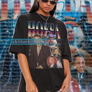 Puede incluir: Camiseta negra de gran tamaño con el texto "HOFFA Jimmy" y retratos de hombres con trajes. La camiseta unisex es de talla 2XL.