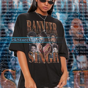 Può includere: T-shirt unisex nera con la scritta dorata "RANVEER SINGH" e una grafica di diversi uomini. La modella indossa una taglia 2XL. Il testo "SickStoreOfficial" è visibile. Per una vestibilità oversize, scegliere una taglia in più.
