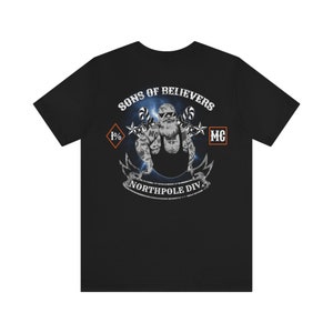 Può includere: T-shirt nero con una grafica di una figura simile a Babbo Natale con tatuaggi e una toppa di club motociclistico che dice "Sons of Believers 1% MC Northpole Div."