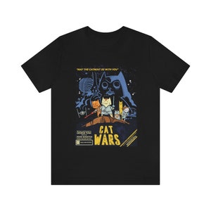 Może przedstawiać: Czarny T-shirt z nadrukiem w stylu vintage przedstawiającym grupę kotów przebranych za postacie z Gwiezdnych Wojen. Na plakacie widnieje napis "Cat Wars" i "Niech mięta kotnia będzie z tobą".