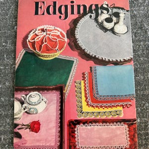Può includere: Un libretto di artigianato vintage Coats & Clark's O.N.T. Edgings Book No. 305 con copertina rosa. La copertina mostra vari bordi in pizzo all'uncinetto su tovaglioli, centrini e biancheria, con quadrati di tessuto colorati e set da tè.