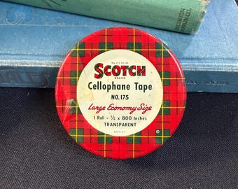 May include: A vintage Scotch brand cellophane tape dispenser. The dispenser is round with a red plaid pattern and the text "Scotch Cellophane Tape" and "Large Economy Size". The roll contains 1/2 x 800 inches of transparent tape.