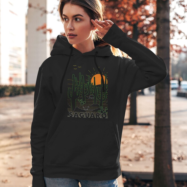 May include: Black hooded sweatshirt with a graphic print of a desert landscape with cacti and a setting sun. The text "SAGUARO" is printed below the graphic.