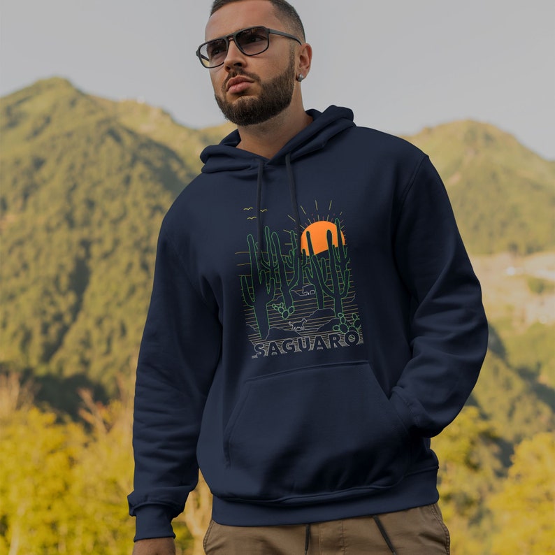 May include: A navy blue hooded sweatshirt with a graphic of a desert landscape featuring cacti and a setting sun. The text "SAGUARO" is printed below the graphic.