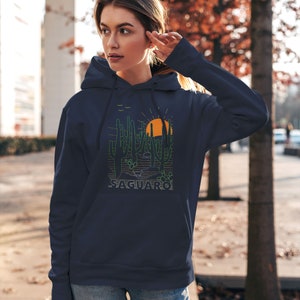 May include: A navy blue hoodie with a graphic of a desert landscape featuring saguaro cacti, a setting sun, and the word "SAGUARO" in green text.