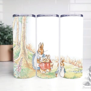 Puede incluir: Tres vasos de acero inoxidable con fondo blanco y una ilustración colorida de Peter Rabbit y su familia en un entorno de bosque.