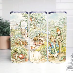 Puede incluir: Tres vasos de acero inoxidable con fondo blanco y una ilustración colorida de una escena de jardín con conejos, pájaros y flores. Los vasos son perfectos para mantener las bebidas frías o calientes.