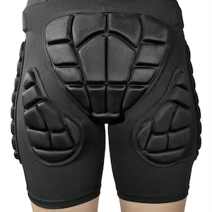 May include: Black protective shorts with padded sections covering the hips, thighs, and tailbone. The shorts are designed to absorb impact and are made of a stretchy, form-fitting material. The padding is segmented for flexibility.