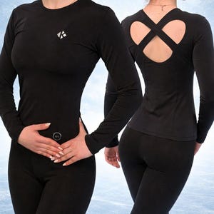 以下が含まれることがあります： 黒色の長袖アスレチックトップスとレギンス。トップスは胸に小さな白いロゴとクロスバックデザインが特徴です。レギンスはぴったりフィットします。スポーツやフィットネス活動に適しています。