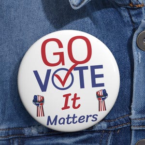 May include: A white button with the words "GO VOTE It Matters" in red and blue. The word "VOTE" has a red checkmark over the "O". The button is on a denim jacket.