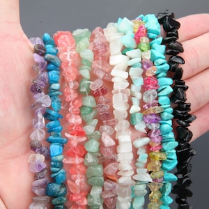 May include: Assortment of chip-shaped gemstone beads in various colours, including turquoise, amethyst, green, pink, and black. The beads are strung on a string and are ready to be used for jewellery making.