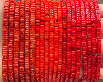 Puede incluir: Primer plano de hilos de cuentas rojas brillantes, pequeñas, planas y en forma de disco. Las cuentas están ensartadas, creando una exhibición texturizada y vibrante. Las cuentas se sostienen en una mano, mostrando su color y forma. Ideal para la fabricación de joyas.