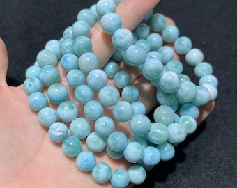 Könnte beinhalten: Ein Stapel blauer und weißer Edelstein-Armbänder aus runden Perlen. Die Armbänder bestehen aus einem hellblauen Stein mit weißen Wirbeln.