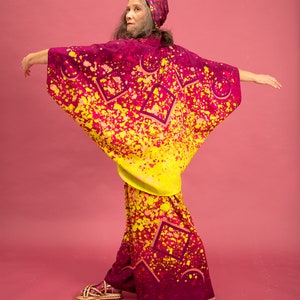 K&ouml;nnte beinhalten: Eine Frau tr&auml;gt einen pink- und gelbfarbenen Kimono mit geometrischem Muster. Der Kimono hat eine weite, flie&szlig;ende Silhouette und ist aus einem leichten Stoff gefertigt.