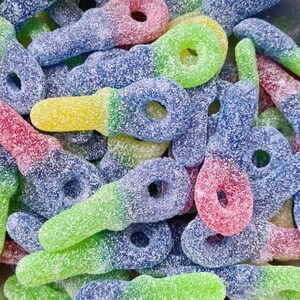 May include: Close-up of colorful, key-shaped gummy candies. The candies are coated in sugar and feature a gradient of colors, including red, blue, green, and yellow. The candies are a sweet treat.