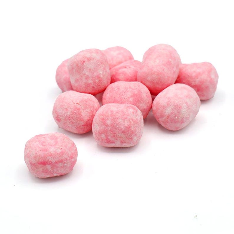 May include: A cluster of pink, round candies with a textured, slightly rough surface. The candies are a light pink color and appear to be coated. The image is set against a plain white background.
