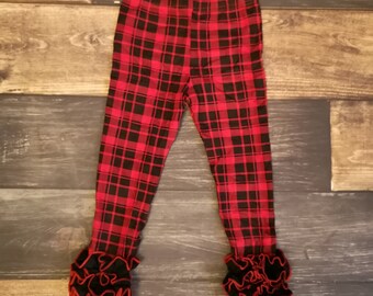 Puede incluir: Leggings de cuadros rojos y negros con ribete de volantes negros y rojos en la parte inferior.