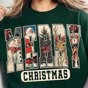 May include: Dark green sweatshirt with the words "MERRY CHRISTMAS" in a vintage style. The letters are filled with images of a snowman, Santa Claus, a Christmas tree, a reindeer, and a nutcracker.
