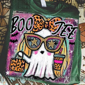 May include: Green sweatshirt with a graphic of a ghost wearing sunglasses and a bow, holding a bag and a drink. The text "BOO Y'ALL" is above the ghost. The ghost has blonde hair and is wearing gold-rimmed sunglasses with star-shaped lenses.