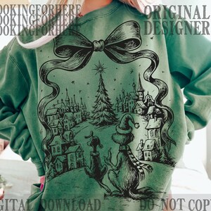May include: Green sweatshirt featuring a black and white illustration of a Christmas scene with a Grinch-like character and a dog. The design includes a Christmas tree, houses, and the text "ORIGINAL DESIGNER" and "DIGITAL DOWNLOAD - DO NOT COPY".