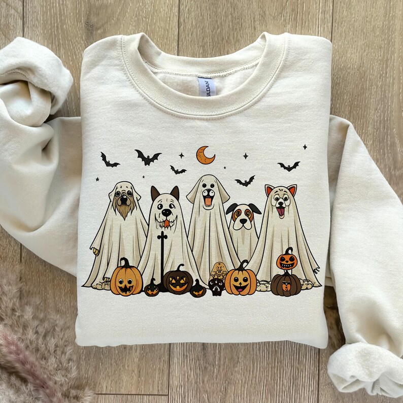Pu&ograve; includere: Felpa color crema con un design di Halloween. La grafica include cinque cani vestiti da fantasmi, con zucche, pipistrelli, una luna crescente e stelle. La felpa &egrave; realizzata in materiale morbido.