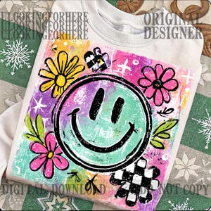 Puede incluir: Una sudadera blanca con un dise&ntilde;o gr&aacute;fico colorido. El dise&ntilde;o presenta una gran cara sonriente rodeada de flores y otros elementos decorativos. El gr&aacute;fico tiene un estilo art&iacute;stico dibujado a mano.