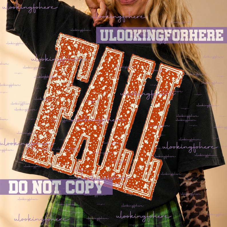 May include: A black short-sleeved t-shirt featuring the word FALL in large, distressed, burnt orange block letters with a white speckled pattern. The design is centered on the chest, and the shirt is worn over a long-sleeved leopard print top.