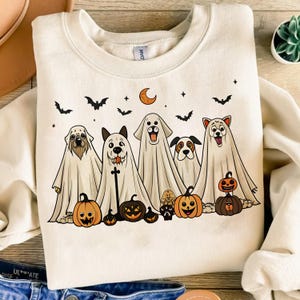 Pu&ograve; includere: Felpa color crema con un design di Halloween. La grafica mostra cinque cani vestiti da fantasmi, con zucche e pipistrelli. Sono inclusi anche una luna crescente e stelle. La felpa &egrave; a girocollo.