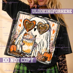 May include: A black t-shirt featuring a graphic illustration of a ghost wearing heart-shaped sunglasses and holding a pumpkin spice latte. The design includes orange pumpkins, autumn leaves, and cinnamon sticks on a striped background.