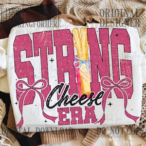 Könnte beinhalten: Weißes Sweatshirt mit dem Text "STRING CHEESE ERA" in verblichenem Rosa. Das Design zeigt eine Illustration von Käsefäden, die mit einer blauen Schleife und rosa Schleifen gebunden sind. Eine verspielte Grafik zum Thema Essen.