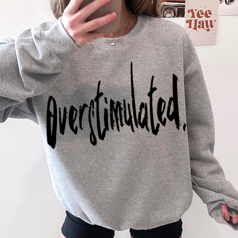 May include: A gray sweatshirt with the text "Overstimulated." printed in black.