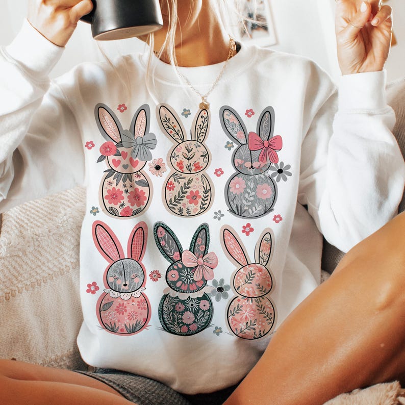 May include: White sweatshirt with a floral bunny rabbit design. The bunnies are wearing bows and have different colored floral patterns.