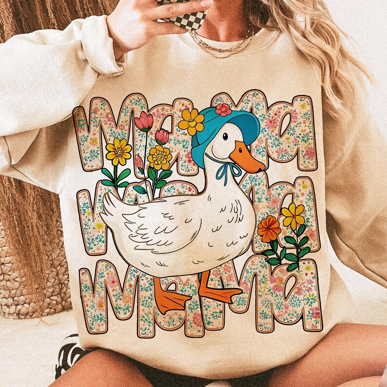 May include: A beige sweatshirt with a white duck wearing a blue hat and a floral pattern. The text "Mama" is repeated three times in a floral design.