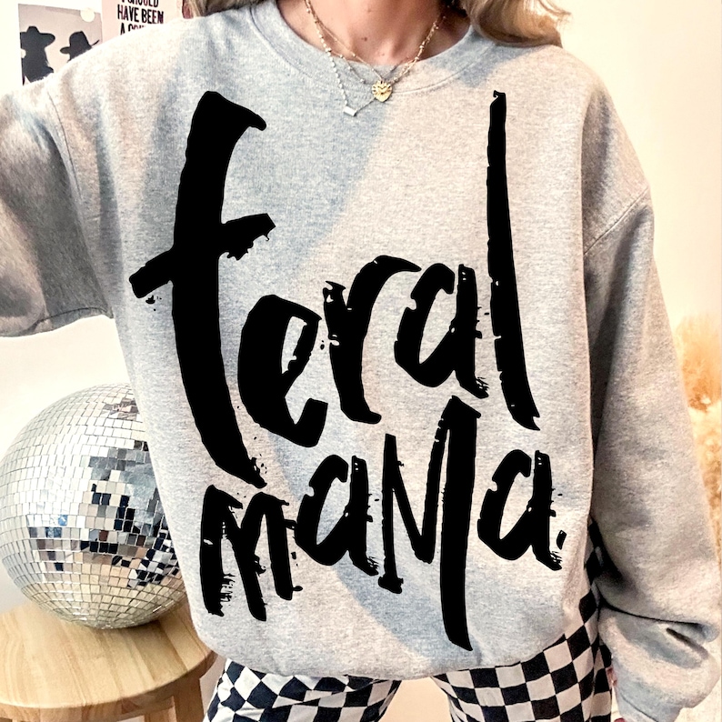 May include: A gray sweatshirt with the text "Feral Mama" printed in black on the front.