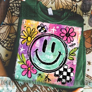 Puede incluir: Sudadera verde con un gr&aacute;fico colorido que presenta una cara sonriente, flores y un dise&ntilde;o a cuadros. El gr&aacute;fico tiene un estilo dibujado a mano con colores brillantes y el texto "DIGITAL DOWNLOAD NOT COPY".