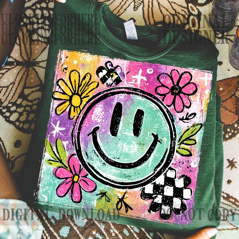 Puede incluir: Sudadera verde con un gr&aacute;fico colorido que presenta una cara sonriente, flores y un dise&ntilde;o a cuadros. El gr&aacute;fico tiene un estilo dibujado a mano con colores brillantes y el texto "DIGITAL DOWNLOAD NOT COPY".