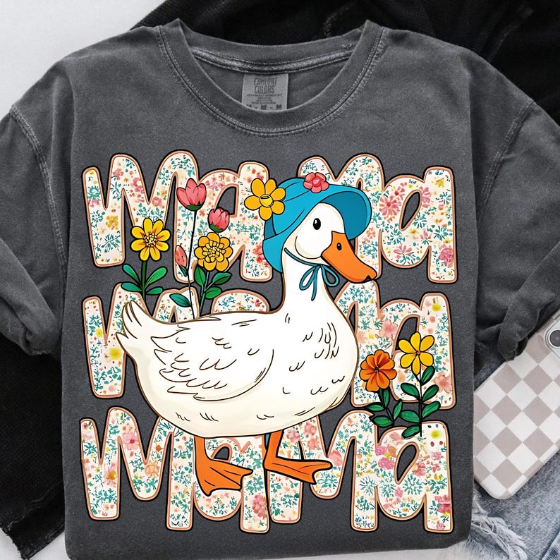 May include: A gray t-shirt with a white duck wearing a blue bonnet and surrounded by colorful flowers. The text "Mama Mama Mama" is printed on the shirt.
