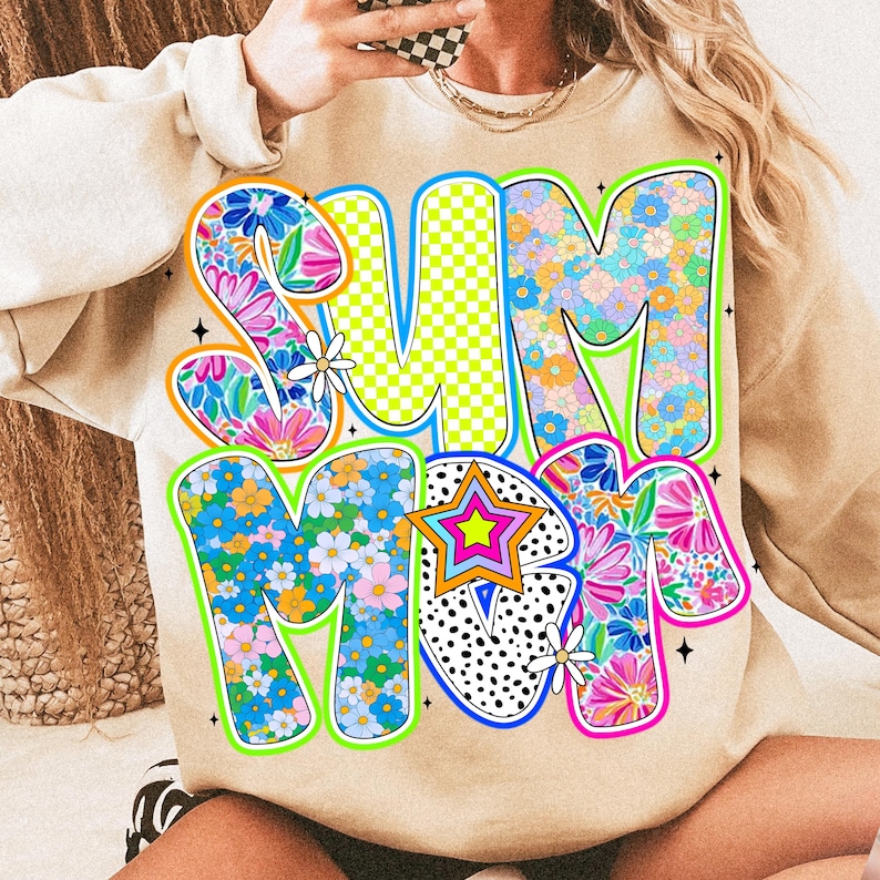 May include: A beige sweatshirt with a colorful graphic print of the word "SUMMER" in a retro style. The letters are decorated with flowers, stars, and geometric patterns.